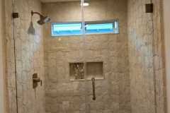 Contemporary bathroom shower featuring a glass enclosure, beige tiles, and a sleek design.