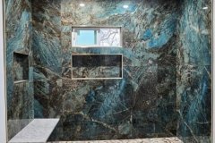 Modern shower area featuring striking blue marble tiles and integrated shelving for a luxurious bathroom look.