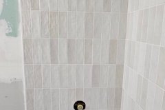 Up of a tiled bathroom wall with beige and cream tiles, showcasing professional tile work.
