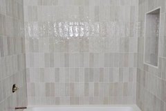 Bathroom with tiled walls and built-in bathtub, showcasing professional tile work by Grapme Tile Works Corp.