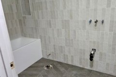 Elegant bathroom wall with beige ceramic tiles, showcasing professional tiling work by Grapme Tile Works Corp.