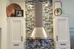 Modern kitchen featuring a stylish tile backsplash, white cabinetry, and stainless steel appliances for a sleek look.