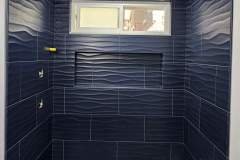 Stylish navy blue wall tiles with textured wave design in a contemporary bathroom interior.