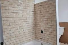 Modern bathroom renovation featuring stylish beige brick tiles and a bathtub.