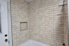 Modern bathroom with beige brick tiles and a built-in niche for toiletries.