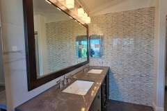 A sleek bathroom vanity featuring textured wall tiles, modern lighting, and a spacious countertop.