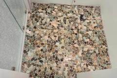 Up of a pebble stone floor with multicolored smooth stones, perfect for outdoor or indoor spaces.