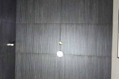 Up of sleek black textured tiles on bathroom wall, showcasing modern design and craftsmanship.