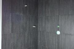 A sleek bathroom corner featuring large black wall tiles creating a contemporary and elegant look.