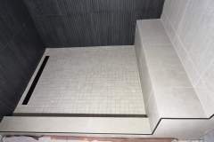 Shower area featuring contemporary tiles, a built-in bench, and efficient drainage for a stylish bathroom upgrade.