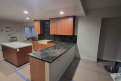 A contemporary kitchen featuring wooden cabinetry and sleek black marble countertops, perfect for stylish living spaces.
