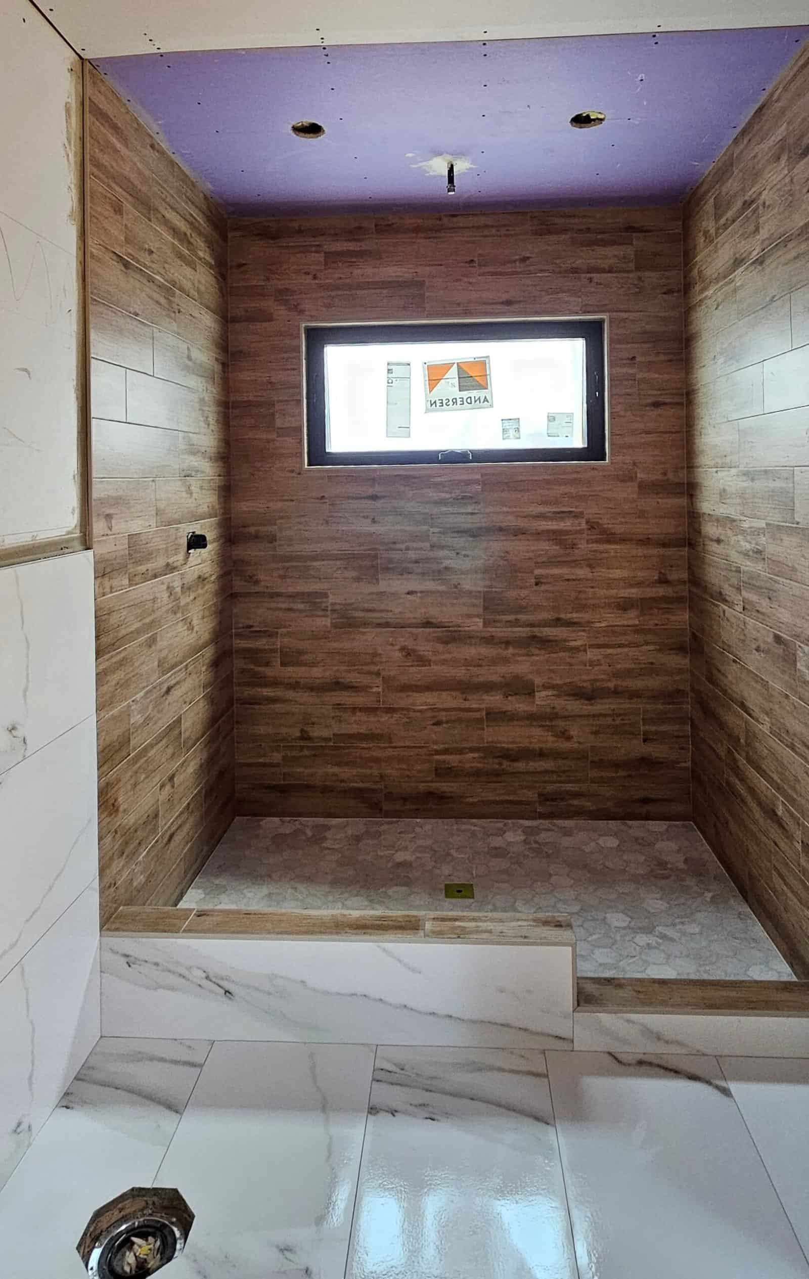 Bathroom with wood-look wall tiles and a window for natural light.