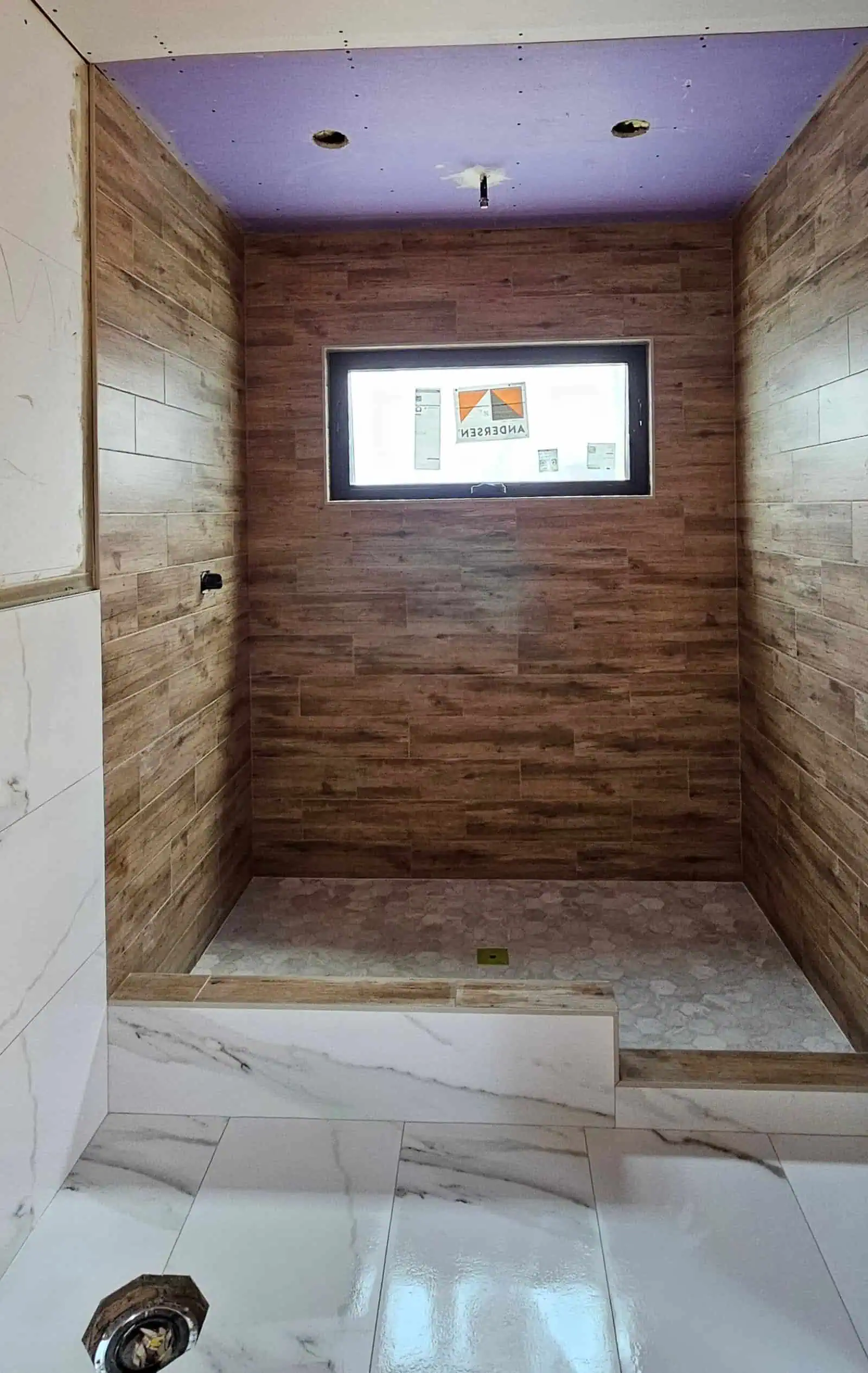 Bathroom with wood-look wall tiles and a window for natural light.