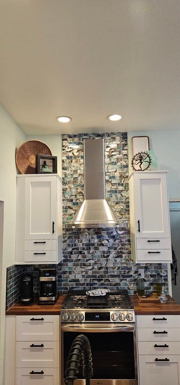 Kitchen backsplash with decorative tiles and stainless steel range hood.
