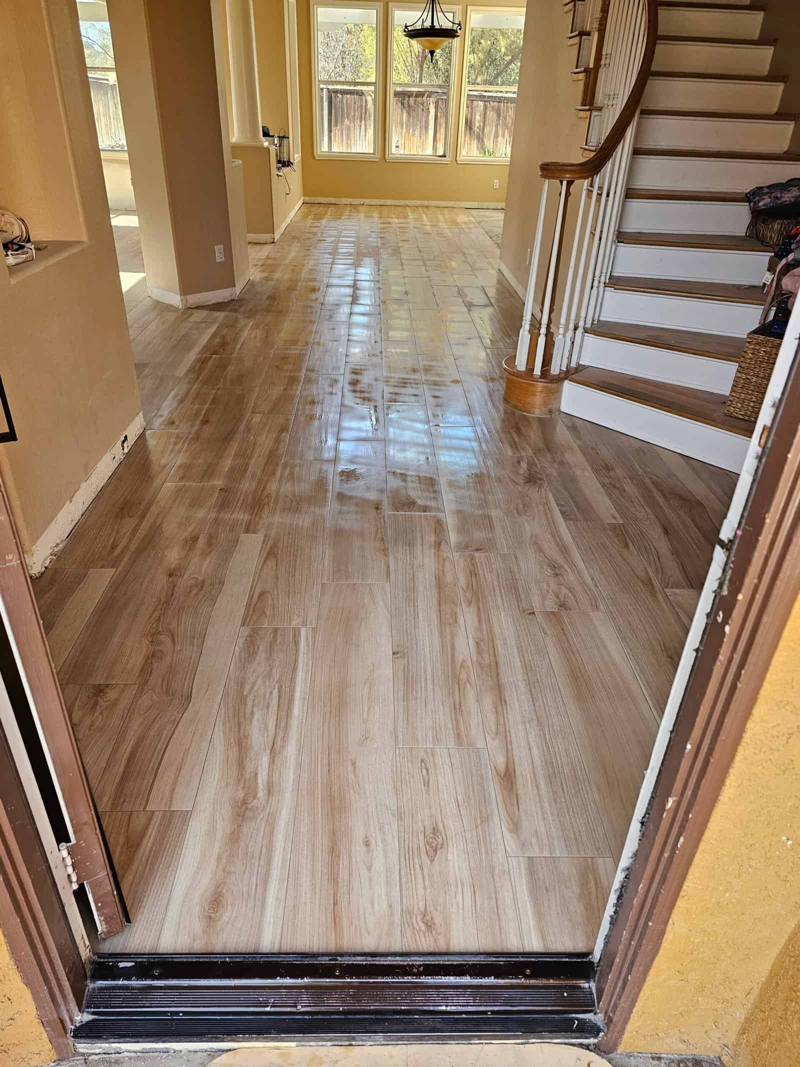 Look tile flooring in a contemporary living space with large windows and staircase.