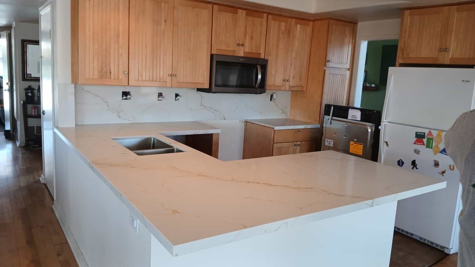 Modern kitchen with marble-style granite countertop and wooden cabinets.